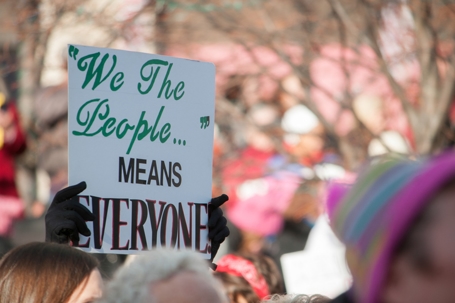 Person holding We the People Sign at protest | Mathur Law Offices
