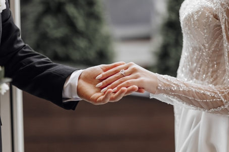Close-up of a groom gently holding the bride’s hand, showcasing her gold wedding ring. | Mathur Law Offices, P.C.