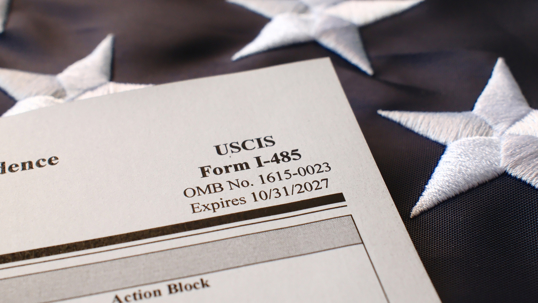 I-485, Application to Register Permanent Residence or Adjust Status blank form lies on United States flag